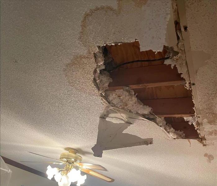 Hole in ceiling surrounded by water stains.
