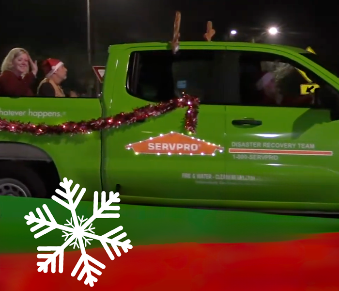 Servpro vehicle decorated with lights and antlers with empoyees waiving in the back of the truck